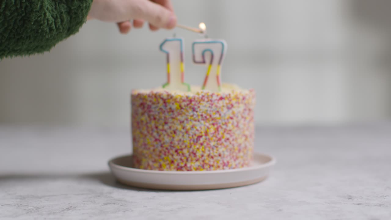 foto de estudio pastel de cumpleaños cubierto con adornos y velas celebrando el decimoséptimo cumpleaños encendido