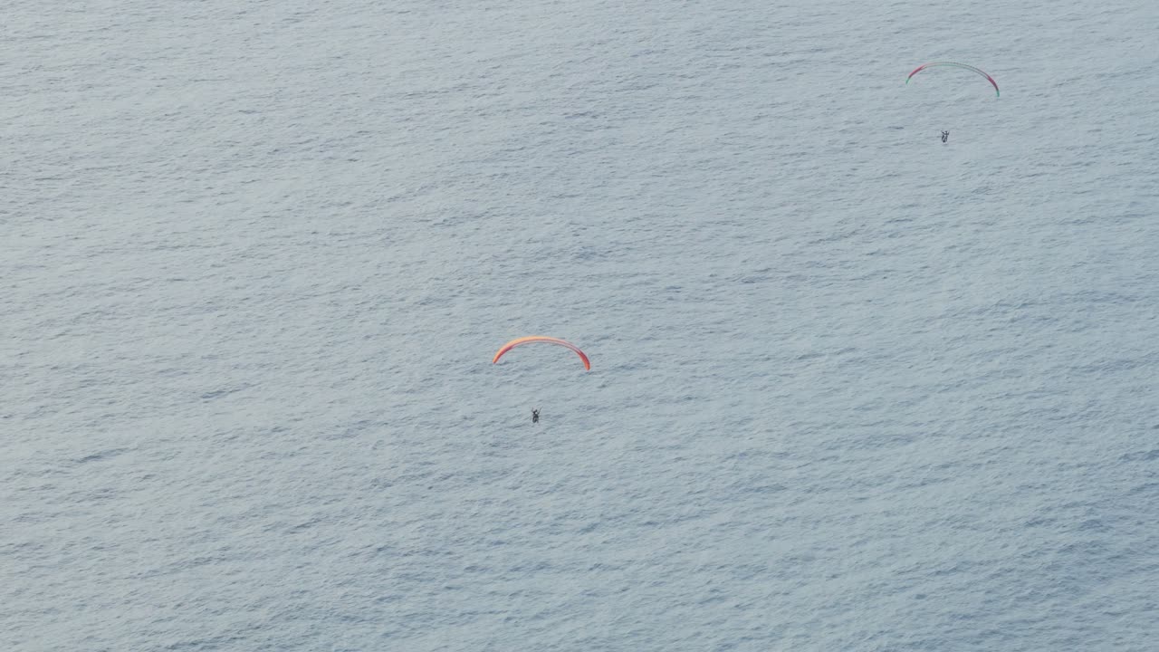 Dua Paralayang Melayang di Atas Air Laut Biru.