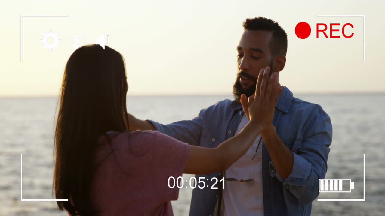 pareja bailando en el mar con cámara grabando animación superpuesta