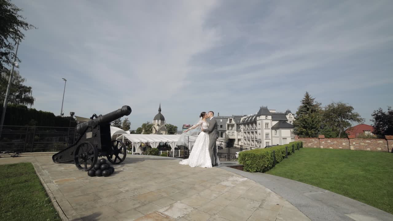 Encantadores recién casados: novia caucásica abrazando al novio en el parque dándose un beso, pareja de boda abrazándose.
