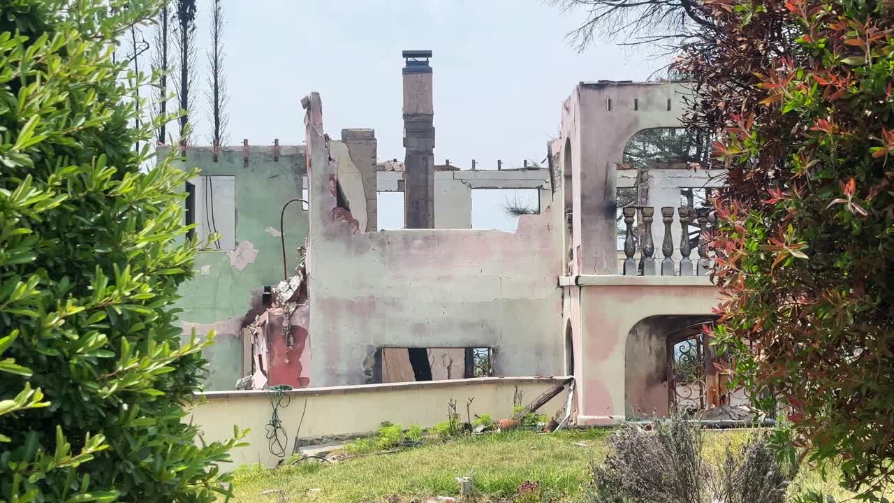 Handheld wide booming up shot of the charred ruins of a home burned by the Eaton Fire in Altadena, California. 4K