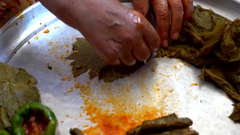 a woman is preparing stuffed grape leaves, leaf wrap, turkish food culture and stuffed leaves