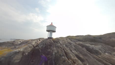 majestic tiny lighthouse with red rooftop on rocky island, closeup fpv drone flyby and orbit