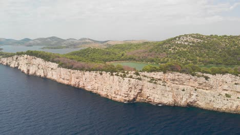 a professional looking aerial of the cliff line of island kornat in croatia, flying backwards showing the landscape