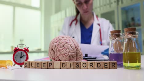 medical concept of a sleep disorder with a brain model, alarm clock, and a doctor in the background