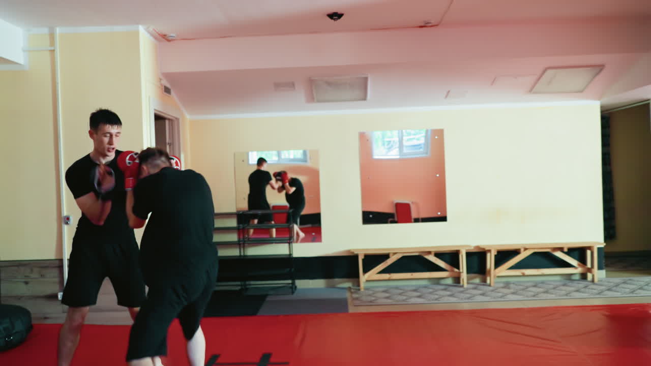 Karate practitioners engaged in sparring inside martial arts gym, wearing gloves, practicing strikes and defensive moves, demonstrating focus, discipline, intense combat training