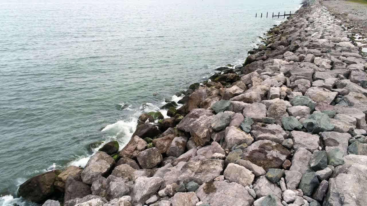 튀는 바다 조수 위의 조수는 바위가 많은 해안 해안선에서 천천히 낮은 각도로 앞으로 부서집니다.