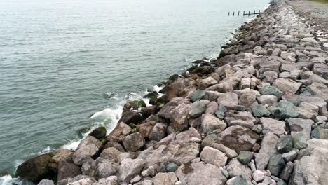 aerial view above splashing ocean tide breaking on rocky coastal shoreline slow low angle forward