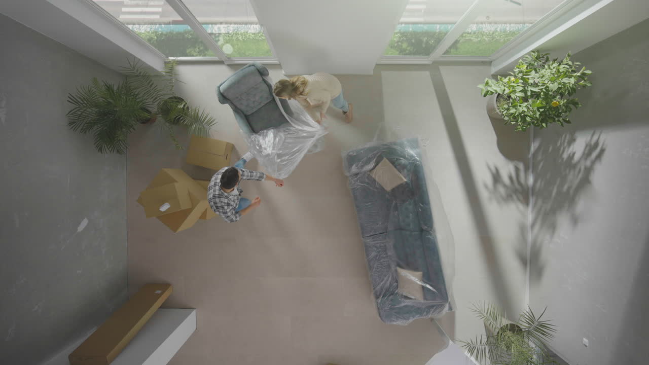 una pareja joven desempaquetando un sillón.