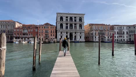 4k follow shot: young male tourist approaching grand canal from a narrow street in venice, italy