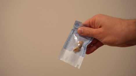 male hand showing two freshly extracted wisdom teeth in a closed sterile bag