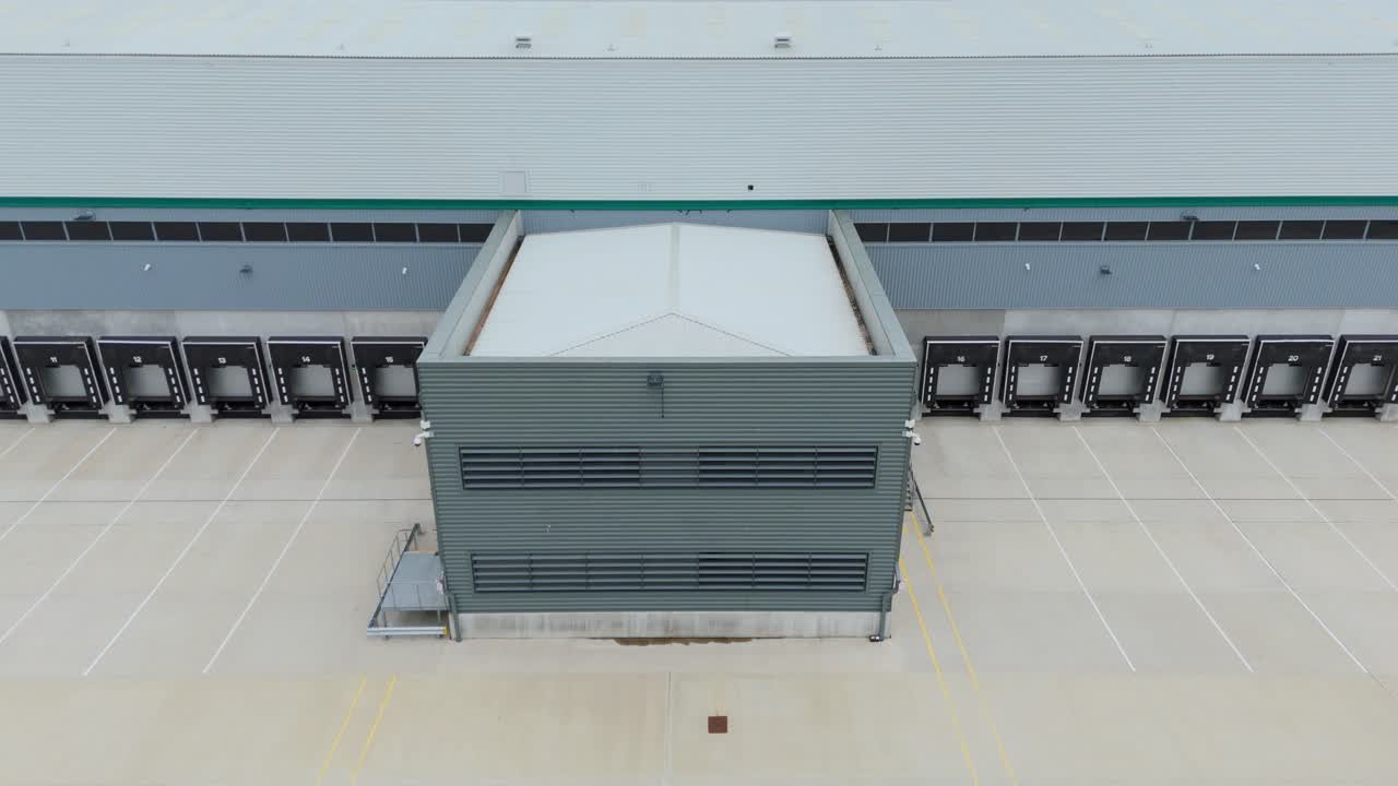 Aerial cinematic drone footage of new industrial warehouse facility with distribution centre loading bays Kettering England UK