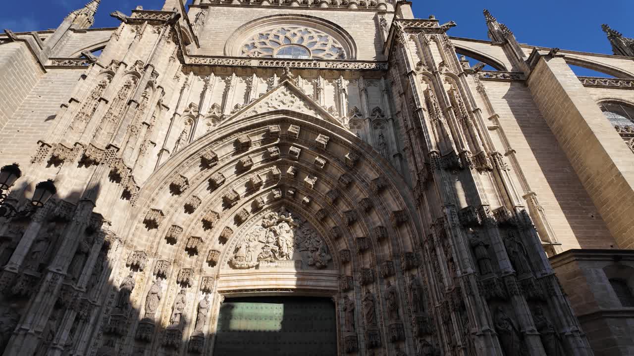 Exterior of Seville Cathedral in Seville, Spain, grand facade and detailed stonework, establishing pan left of intricate stonework