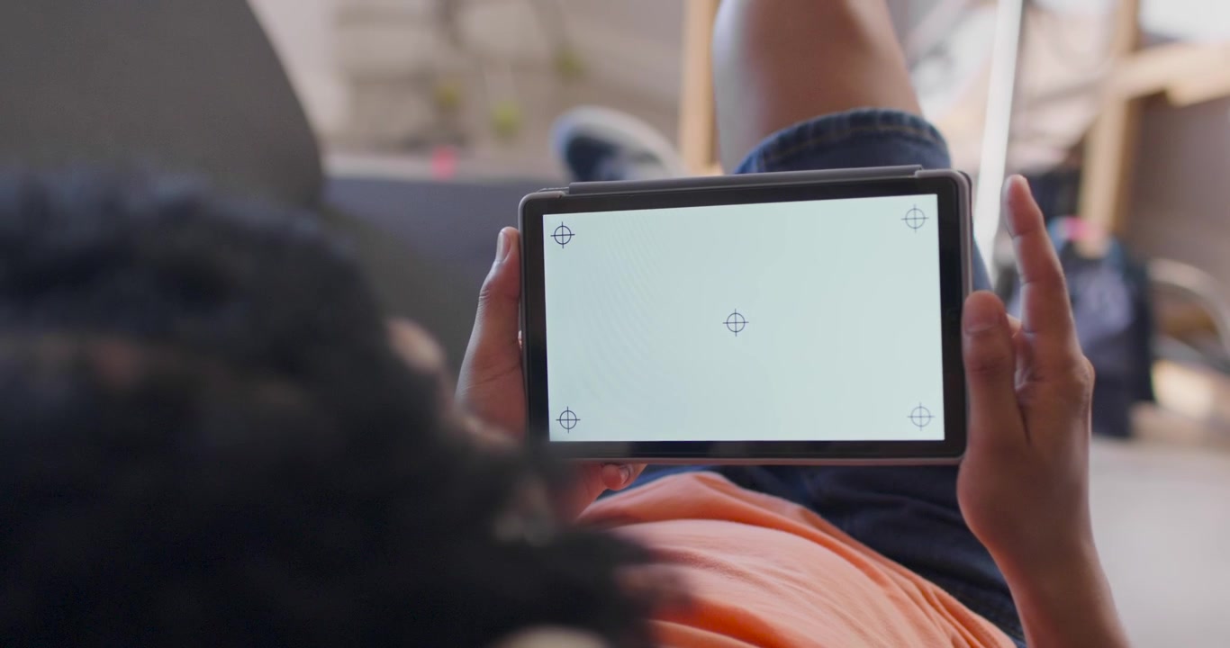 Reclining teen settling on couch and adjusting tablet grip while viewing crosshair for calibration