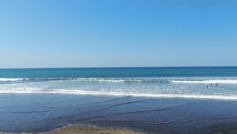 costa rica beach drone fliying through coconout trees and going into the sea over the water in the pacific ocean on a sunny day