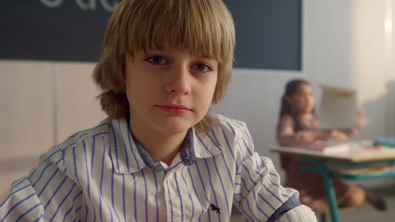 мужчина, сидящий за столом в школе. улыбающийся мальчик смотрит в камеру.