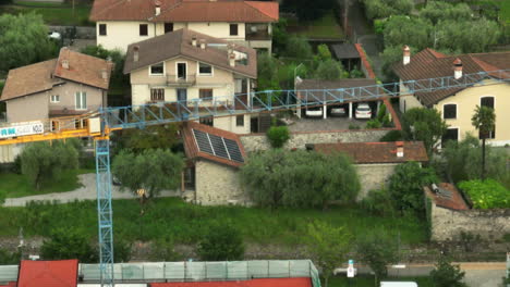 tower crane erected at building site near residential village in brescia, italy. drone sideways, tilt-down