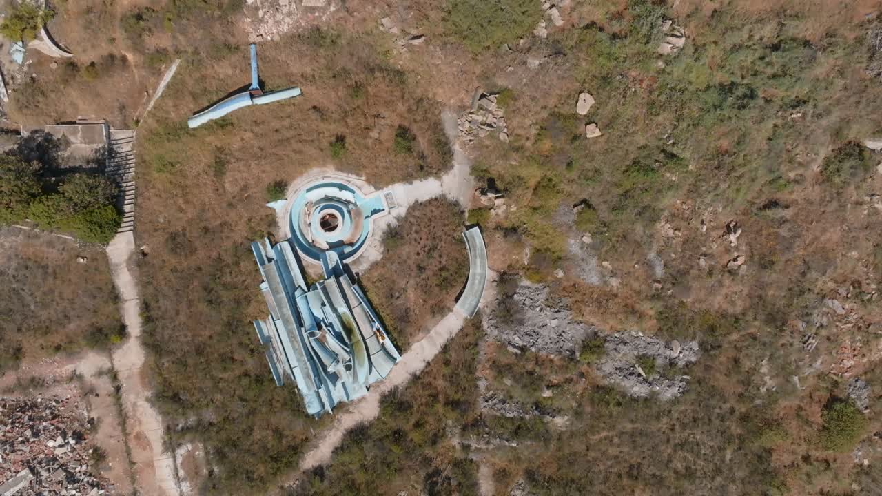 разбитые водные горки и бассейны в грязном сухом красно-коричневом ландшафте, с воздуха