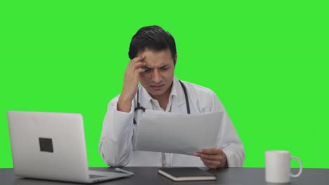 Stressed-and-tensed-Indian-doctor-checking-medical-reports-Green-screen