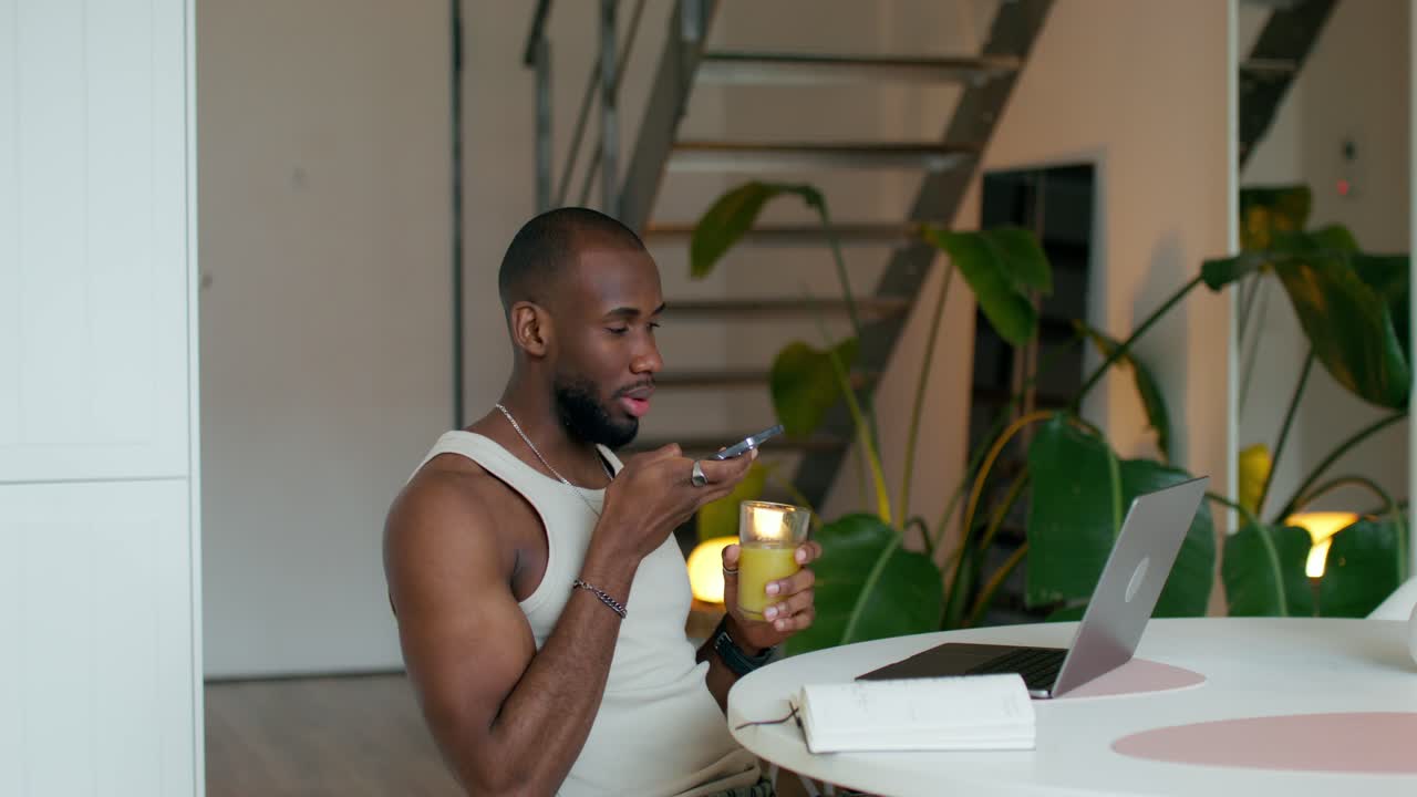 Man using smartphone and laptop while having breakfast in home office