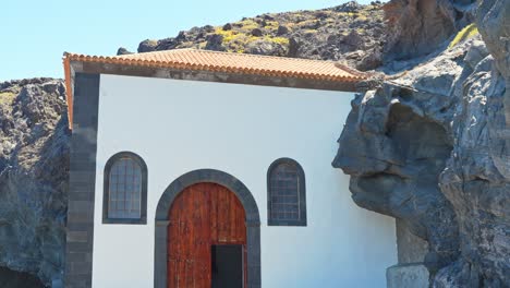 typical white canary style holiday house near rocky cliff in tenerife