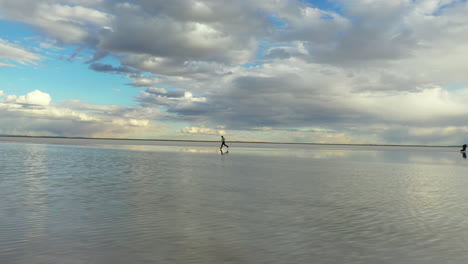hombre corriendo en salinas con reflejo del cielo en el agua y horizonte interminable