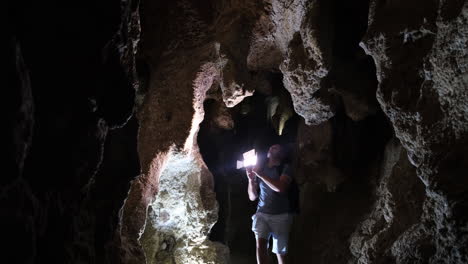 a male archaeologist with a flashlight in a cave he examines the dungeon a male archaeologist with a flashlight in a cave he examines the dungeon speleology dark tunnel