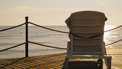 lounge for relaxation is on the pier turned to the rising sun over the sea 4k video