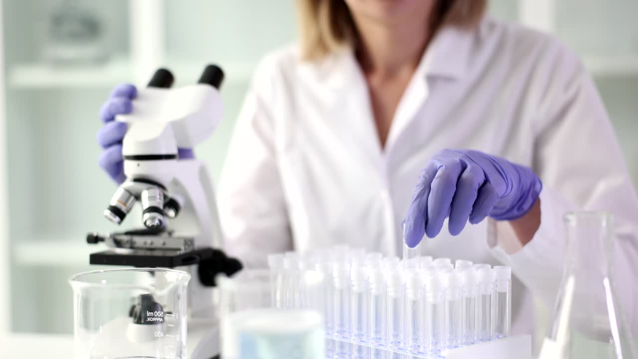 Assistente de laboratório pega tubo de ensaio de vidro para experimento.