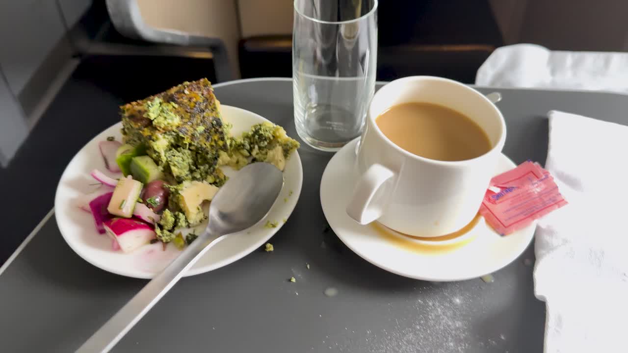 Coffee spills onto airplane tray table during turbulence, with meal and utensils shifting slightly