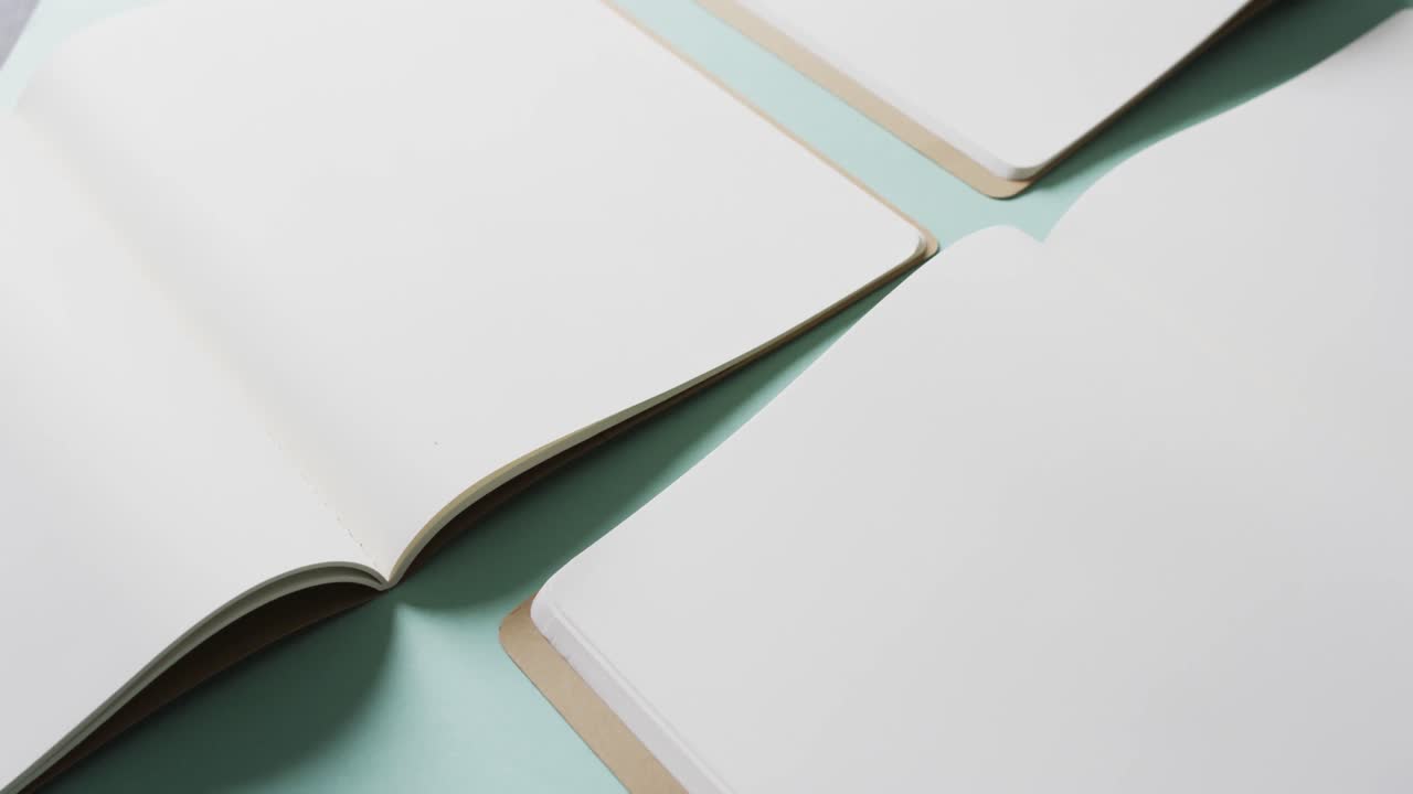 Close up of open blank books with copy space on green background in slow motion