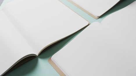 close up of open blank books with copy space on green background in slow motion