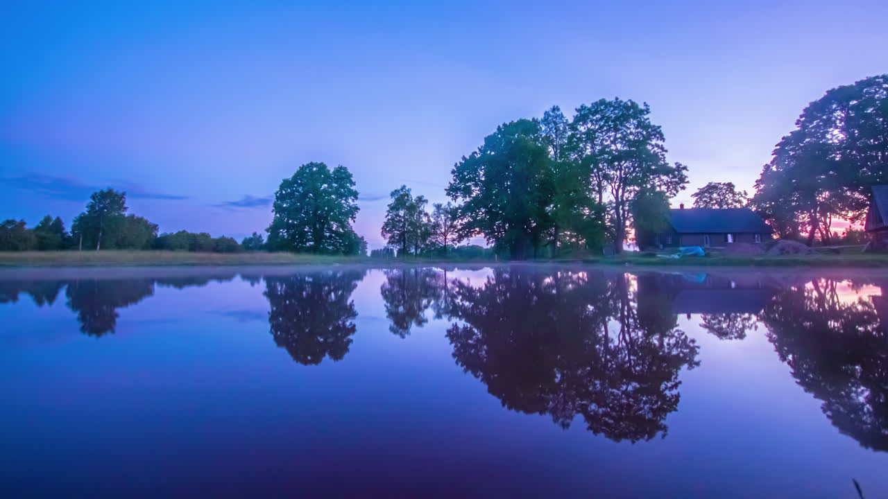 이른 아침에 호수 옆에 있는 나무 오두막의 타임랩스 샷