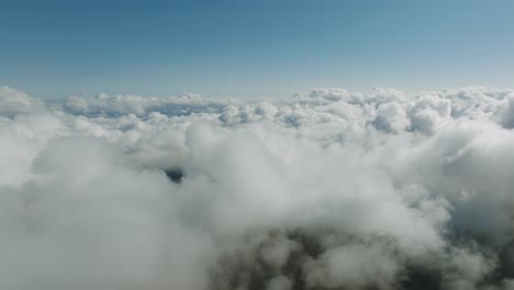 aerial flyover revealing a ocean of white clouds stretching endlessly under clear blue skies