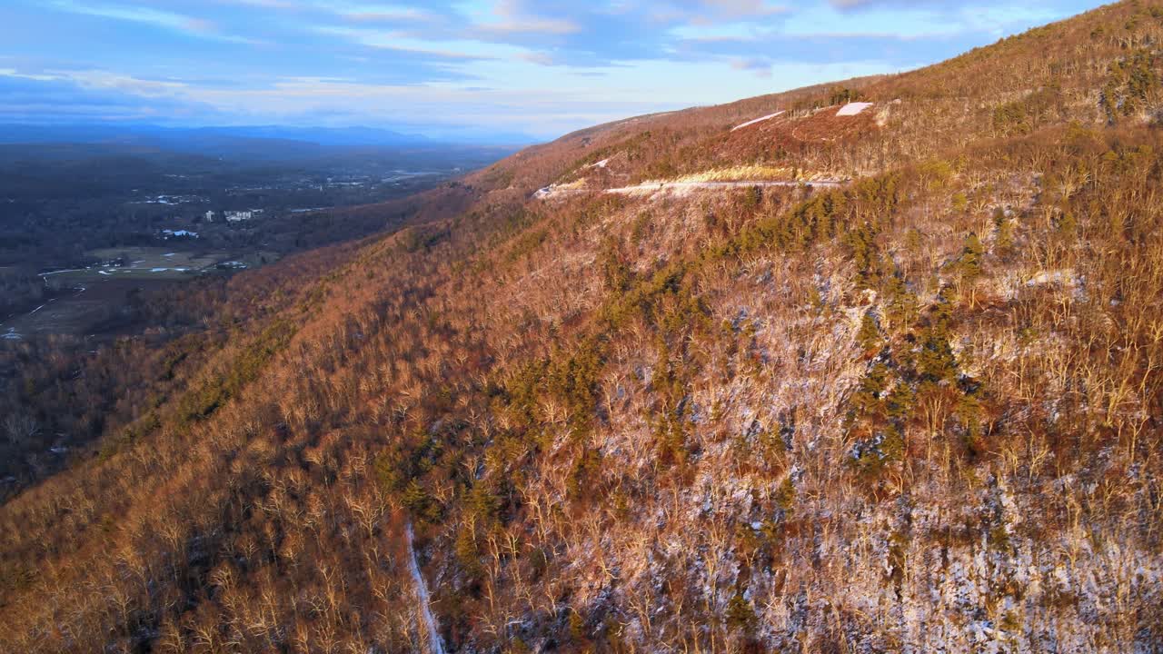 겨울철 일몰의 황금시간 동안 애팔래치아 산맥에서 겨울 동안 눈이 가볍게 코팅된 숲이 우거진 산골짜기의 공중 영상