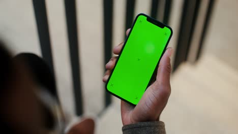 persona sosteniendo un teléfono con una pantalla verde