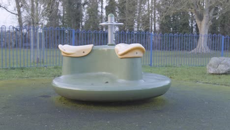 an empty children’s playground with a spinning carousel, in central london on a cold cloudy day