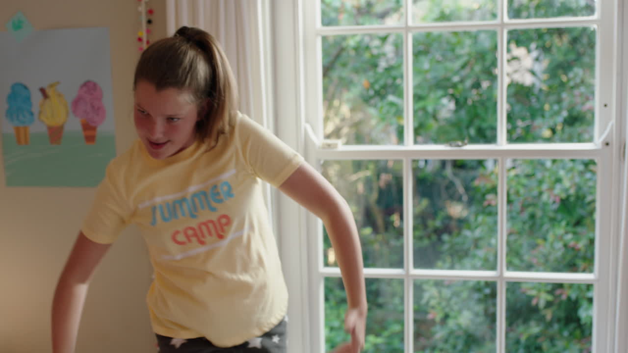 happy teenage girl dancing in bedroom having fun dance celebrating weekend feeling positive wearing pajamas at home