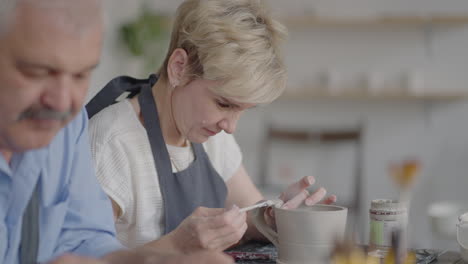 Three-elderly-people-work-on-a-potter's-wheel-in-slow-motion