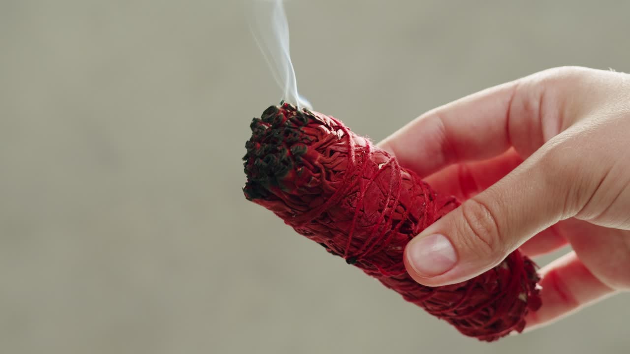 Person holding Palo Santo wood stick in hand, aromatic Palo Santo burning on black background, smoke spreading around, slow motion video clip, high quality 4k close up footage. High quality 4k footage