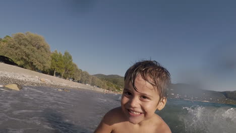 footage of two years old boy, playing with waves at santova beach, kalamata, greece