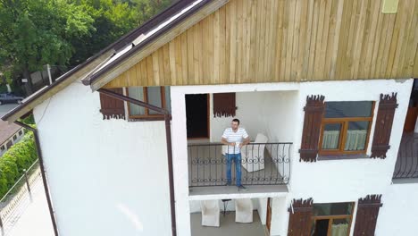 man relaxing on balcony. handsome man standing out of home on balcony and drinking coffee in the morning