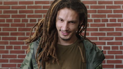 retrato de un atractivo joven de raza mixta con dreadlocks sonriendo feliz mirando relajado a la cámara