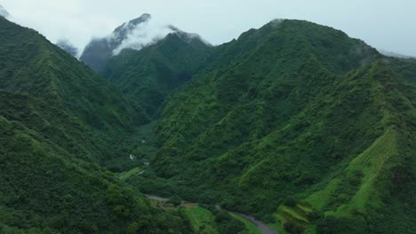 tahiti french polynesia teahupoo aerial drone raining fog mountain peaks river morning grey gray season wet green point faremahora village town south pacific mount tohivea island backwards pan up