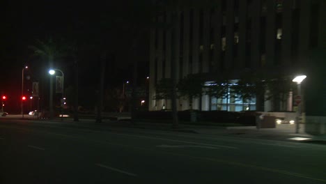 a car travels along a street at night in century city los angeles as seen through the rear window at an angle 2