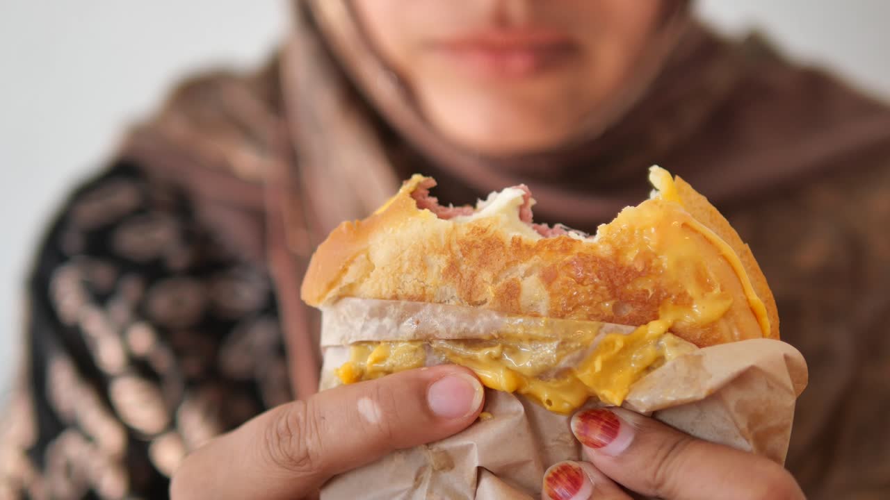Primo piano di una persona che mangia un hamburger