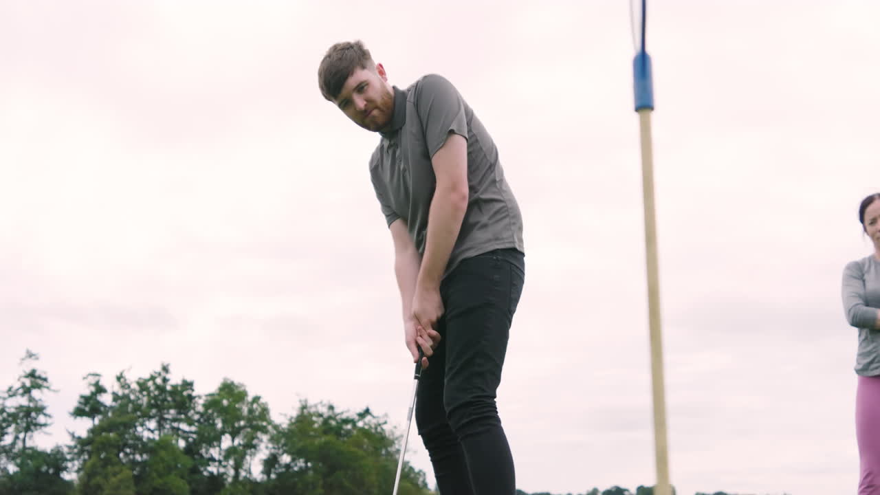 Male golf player playing golf, hitting the ball with club on a golf course