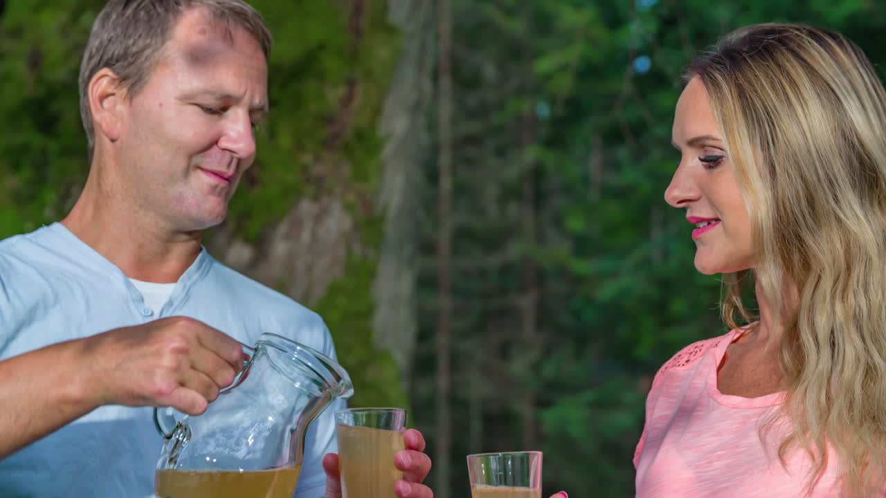 Man's hands pour out apple juice to young beautiful woman. Slow motion