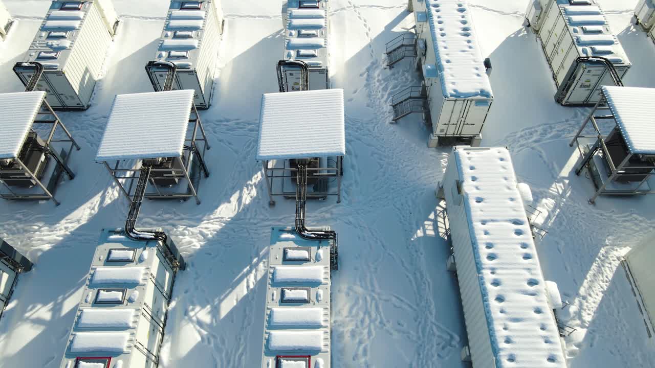 Low altitude pass revealing detailed power storage modules and cables at winter electricity facility