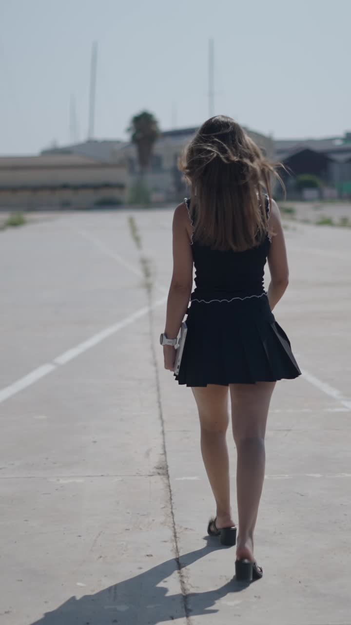 A woman walks away from the camera holding a book